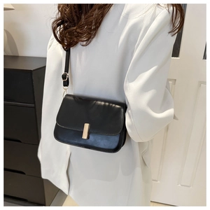 Sac bandoulière noir chic avec boucle dorée porté par mannequin pour le style