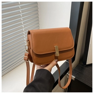 Détail du sac bandoulière en cuir marron avec un fermoir rotatif rectangulaire doré