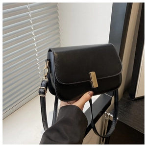 Détail d'un sac à main en cuir noir mat avec fermoir rotatif rectangulaire doré sécurisé