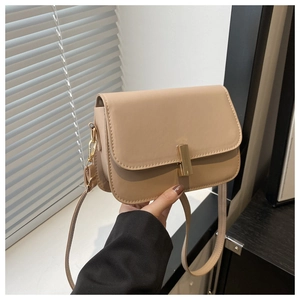 Détail d'un sac bandoulière en cuir beige avec un fermoir rectangulaire doré élégant