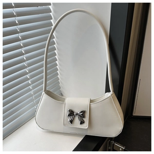 Detailed shot of white crescent bag featuring a metallic bow and soft lighting shadow