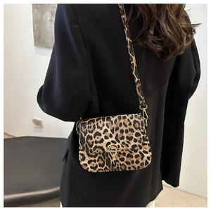 Détail du sac selle léopard avec fermoir doré sur fond de veste de costume noire