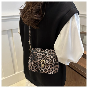 Sac bandoulière léopard avec détails dorés porté par un mannequin dans un décor minimaliste