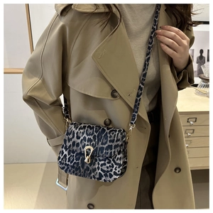 Vue détaillée du sac léopard avec boucle en métal doré porté sur un trench-coat