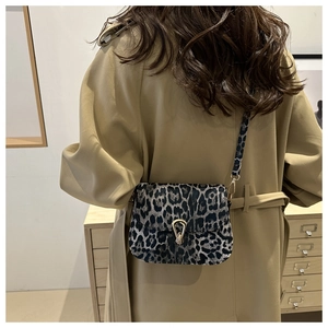 Détail du sac bandoulière léopard avec boucle dorée sur un trench-coat kaki