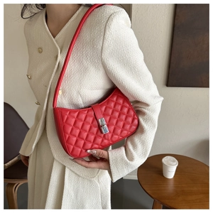 Détail du sac à bandoulière matelassé rouge avec fermoir argenté sur manteau chic
