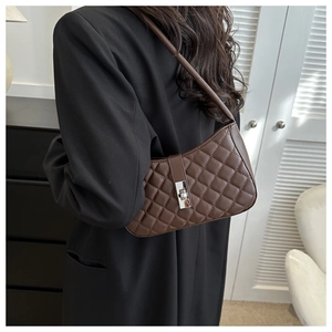 Détail d'un sac sous le bras marron matelassé avec fermoir argenté et texture cuir PU