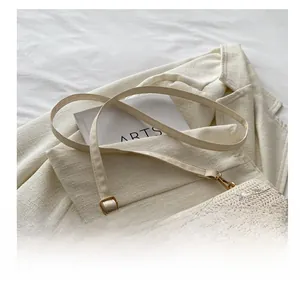 Detail of floral embroidery on a woven cream shoulder bag with adjustable leather strap