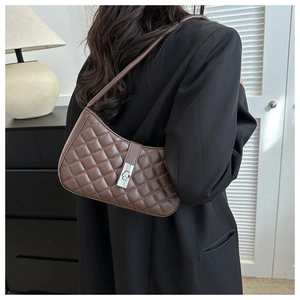 Sac sous le bras matelassé marron avec fermoir rotatif argenté porté par un mannequin