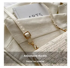 Detail of adjustable strap with gold buckle on cream woven shoulder bag with floral embroidery