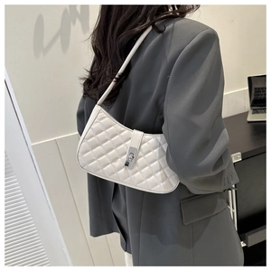 Détail du sac baguette blanc matelassé avec fermoir rotatif sur veste de tailleur