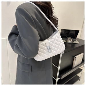 Détail de la texture matelassée blanche et du fermoir rotatif en métal argenté du sac porté