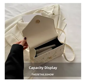 Detail of floral embroidery on cream crossbody bag showing interior phone capacity