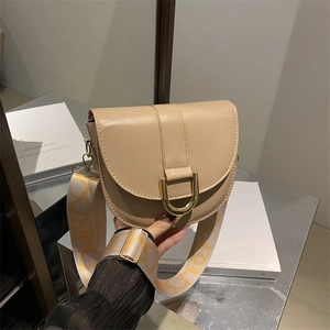 Elegant beige leather saddle bag with wide woven strap and gold U-shaped metal lock