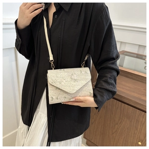 Détail du sac bandoulière en paille beige avec broderie florale et fermoir doré
