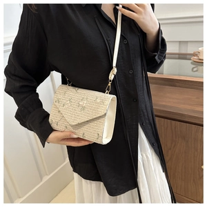 Détail du sac à bandoulière en paille beige avec broderie florale vert clair délicate