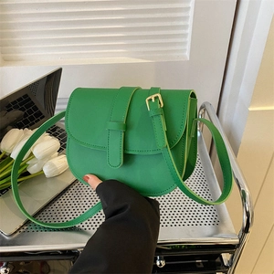 Bright green faux leather saddle crossbody bag with gold buckle and long strap
