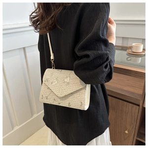 Détail de broderie florale sur un sac bandoulière en paille tissée pour femme