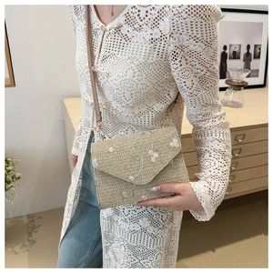 Détail du sac en paille tissé avec broderie de fleurs roses et bandoulière en cuir