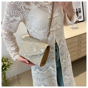 Détail du sac bandoulière en paille beige avec broderie florale et sangle en cuir