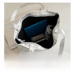 Spacious interior of white croc-embossed tote bag holding tablet, wallet and umbrella