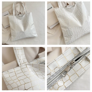Macro view of white croc-embossed tote bag with golden crackle finish and silver zipper