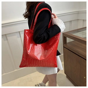 Macro view of glossy red crocodile pattern faux leather on a large tote bag