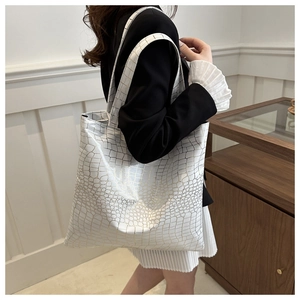 Detail of white large tote bag with golden crocodile texture worn by model