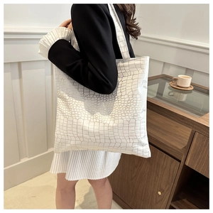 Close-up of white oversized tote bag showing textured crocodile pattern and gold hardware
