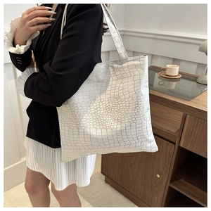 Detailed view of white crocodile pattern tote bag featuring gold texture in a lifestyle setting