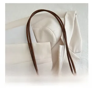 Close-up of brown leather tote bag with litchi texture on a white suit and magazine