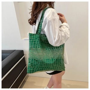Detail of green crocodile textured large tote bag showing glossy finish and handle