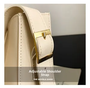 Detail of cream leather shoulder strap with polished gold adjustable metal buckle