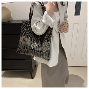Lifestyle view of a large black crocodile pattern tote bag held by a model in a white blazer