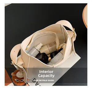 Detail of spacious interior of cream shoulder bag with plush bear charm and zipper