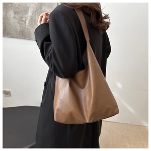 Detail view of large brown PU leather tote bag showing soft texture and slouchy design
