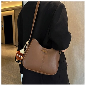 Brown soft leather hobo bag featuring FASHION embossing and a cute plush monster charm