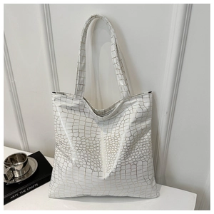 Detail of white tote bag featuring crocodile pattern texture and gold-lined accents