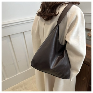 Detail view of large dark brown tote bag with smooth faux leather texture for daily commute