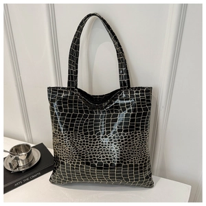 Detail of glossy black crocodile pattern leather tote with golden finish highlights