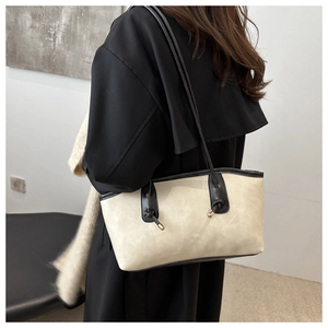Detail of minimalist beige tote bag with black straps worn over a shoulder