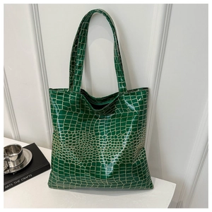 Detailed view of green crocodile pattern tote bag with glossy metallic gold grid finish