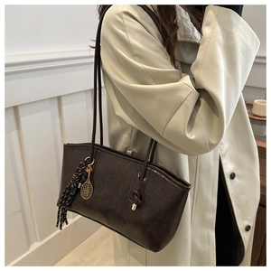 Detail of dark brown tote bag with vintage leather texture and tennis racket charm