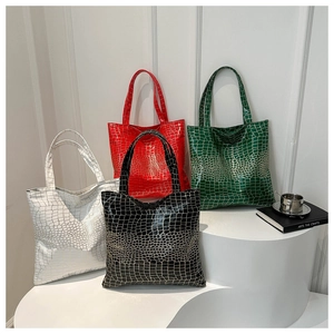 Detail of four glossy crocodile pattern tote bags in white, red, green and black colors