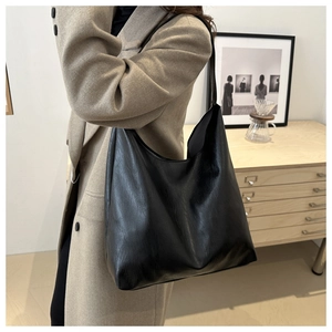 Detailed view of black minimalist tote bag with fine leather texture and slim shoulder strap