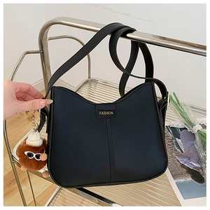Detail of black PU leather half-moon crossbody bag with golden fashion logo and plush charm