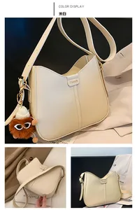 Detail view of cream white hobo bag with gold lettering and cute brown plush charm