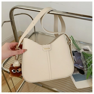 Detail of off-white crescent bag with FASHION label and cute brown pompom charm