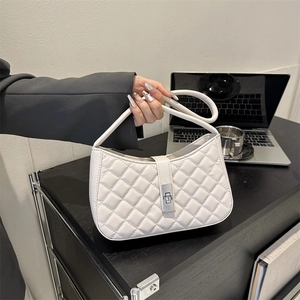 Sac sous le bras matelassé blanc avec fermoir rotatif argenté dans un bureau urbain