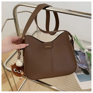 Detail of dark brown leather crescent bag with fashion logo and plush bear charm